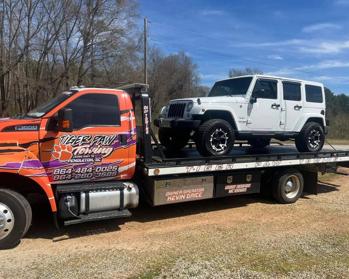 Tiger Paw Towing Truck safely transporting white 4-Door Jeep Wrangler.